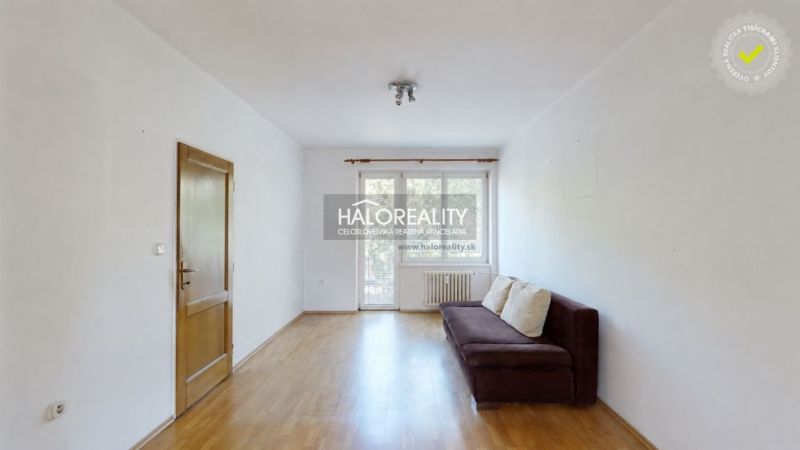 Living room with a sofa and wood-patterned flooring in a three-room apartment.