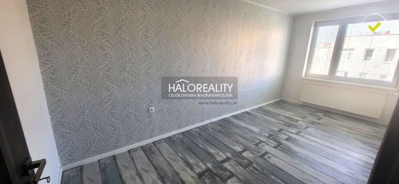 A room in a 3-room apartment with decorative wallpaper and a wooden decor floor.