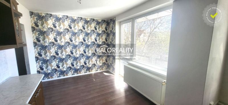 A room in a 3-room apartment with striking wallpaper and a wooden decor floor.