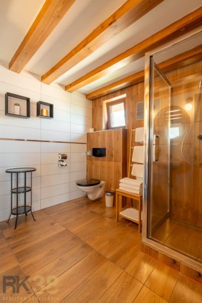 Bathroom with a shower, floor with wood decor, table and shelf.