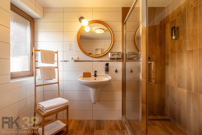 A bathroom with a sink, shower, and floor with a wooden decor in a 3-room apartment.