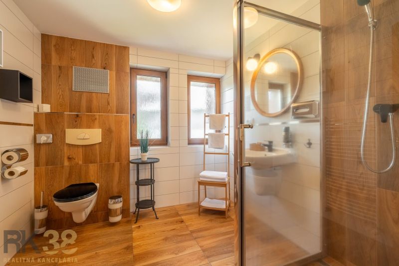 A modern bathroom in a 3-room apartment, with a wooden decor floor and a shower corner.