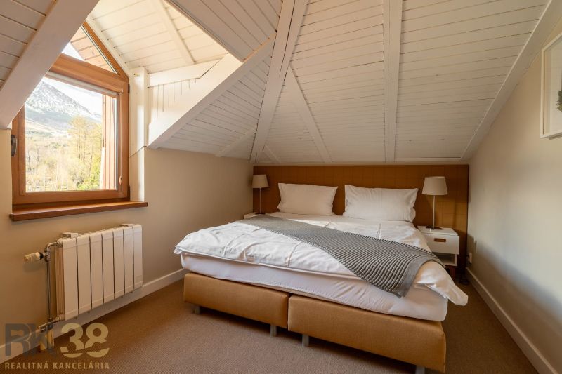 A bedroom in a 3-room apartment with a view of the mountains and a wooden ceiling.