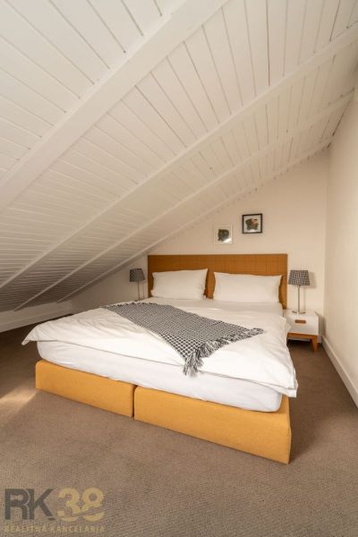 Attic bedroom in a 3-room apartment with a double bed and decorative lamps.