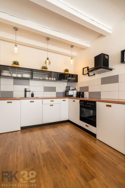 A kitchen in a 3-room apartment with a wooden decor floor and pendant lights.