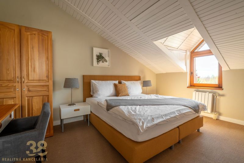 Attic bedroom with a double bed in a 3-room apartment, wooden ceiling, carpet.