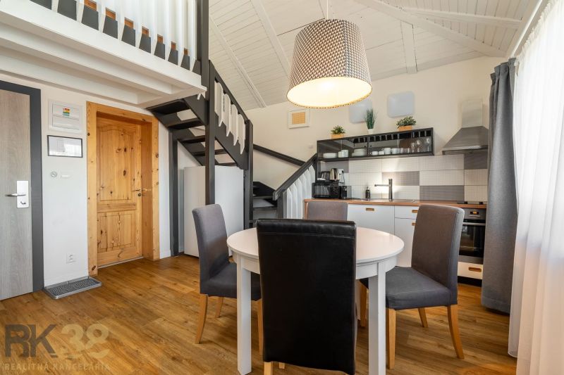 Interior of a 3-room apartment with a kitchen, dining table, and wood-patterned flooring.