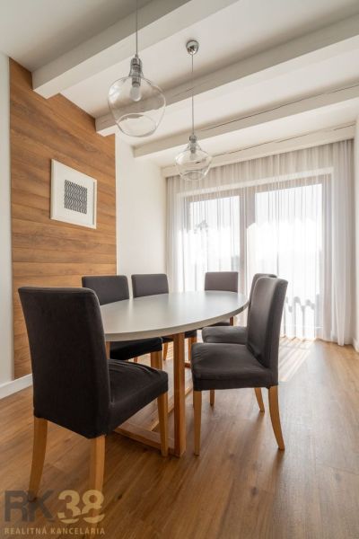 Dining table with dark chairs, bright interior, and floor with wood decor.