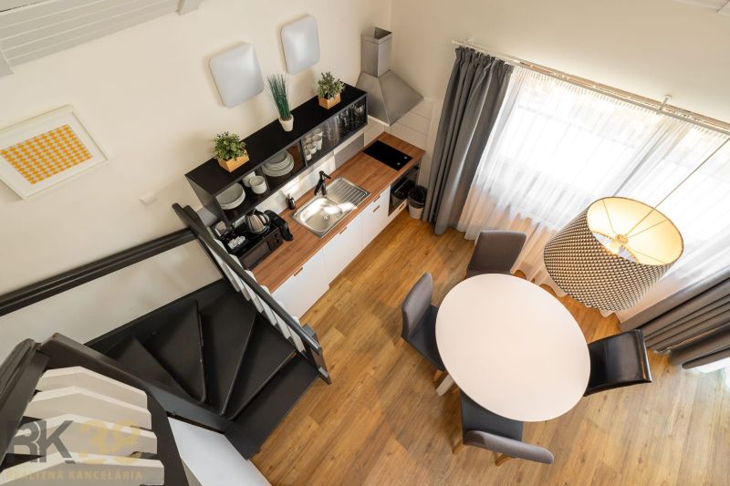 Interior of a 3-room apartment with a wooden decor floor, kitchen unit, and staircase.