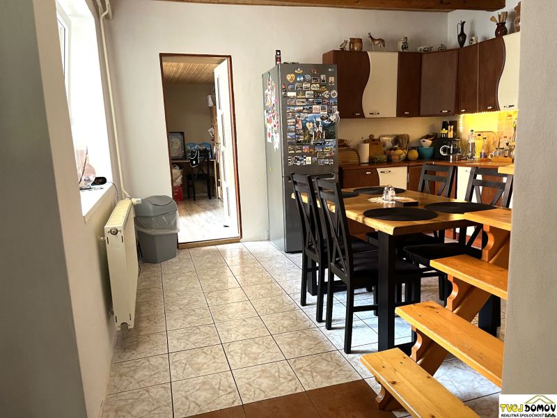 A kitchen in a family house with a dining table and magnets on the refrigerator.