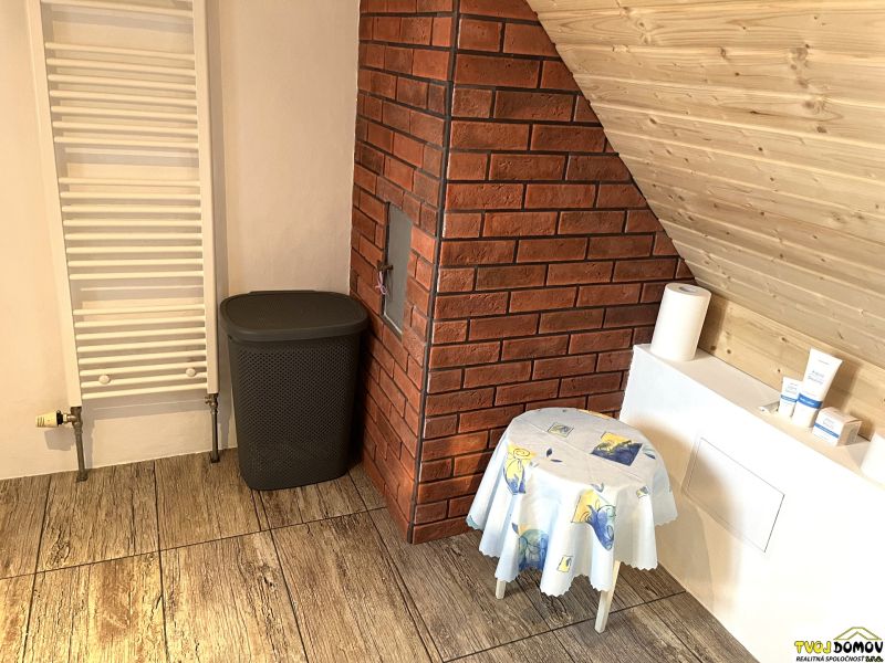 A bathroom in a family house with a wooden decor floor, red bricks, and a ladder radiator.