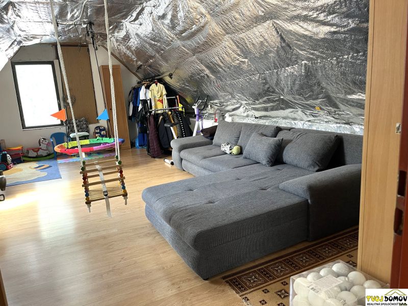 An attic room in a family house with a hanging swing, a wooden decor floor, and toys.