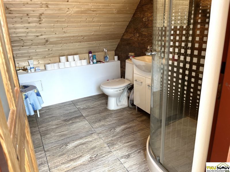 A bathroom with wooden paneling, a shower enclosure, and a floor with a wooden decor, in a family house.