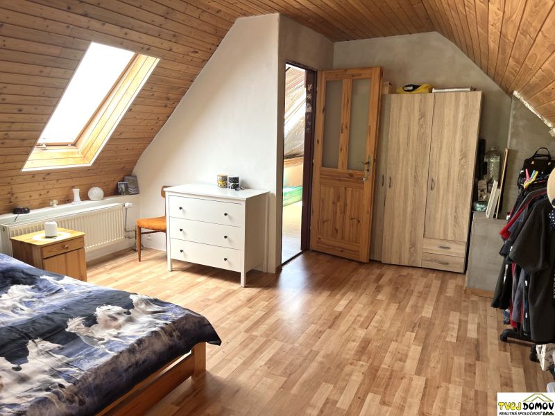 Attic room in a family house with a wooden decor floor and a skylight.