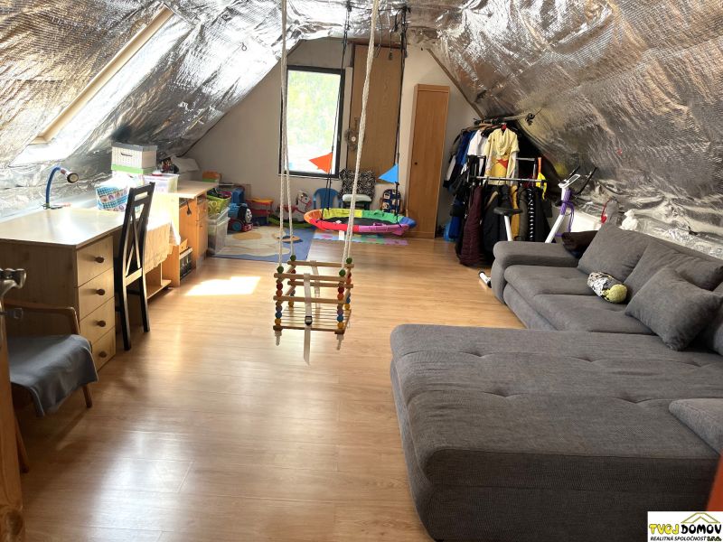 Attic room with a swing, seating, and a wooden decor floor in a family house.