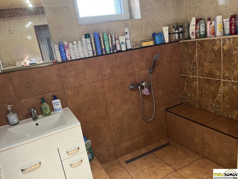 Bathroom in a family house with tiles and lots of cosmetic products on the shelves.