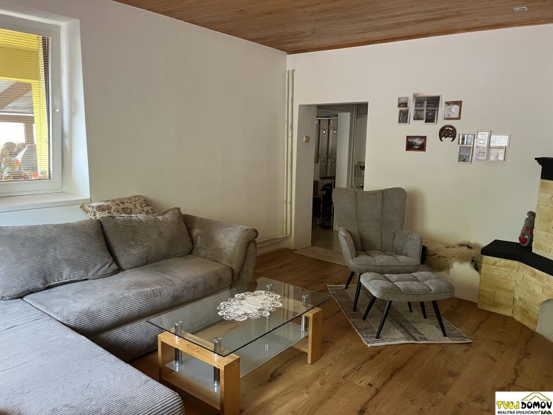 Living room with a comfortable sofa, armchair, and wooden decor flooring in a family house.