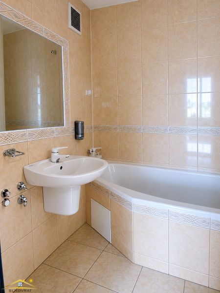 A bathroom with a corner bathtub and a sink in a 3-room apartment.