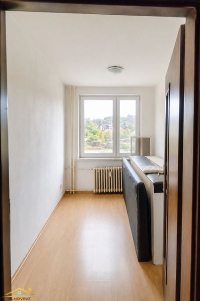 A room in a 3-room apartment with a wooden decor floor and a large window.