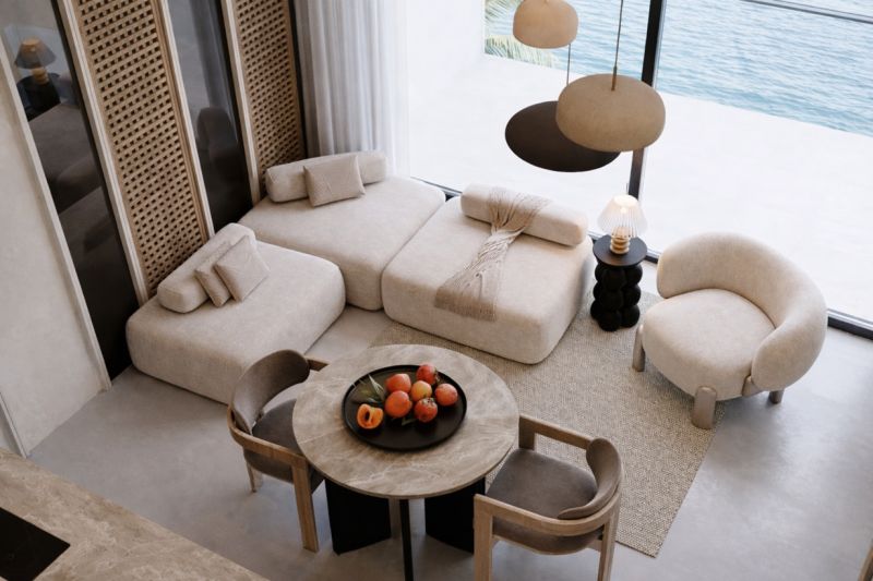 Living space with comfortable sofas, a round table, and a view of the sea.