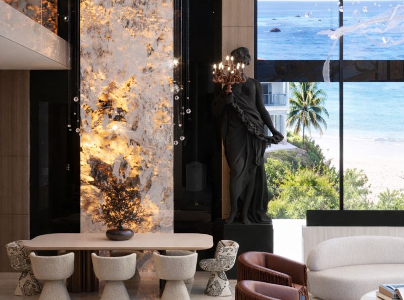 A dining room in a 5 or more bedroom apartment with a view of the beach, featuring a statue and decoration.