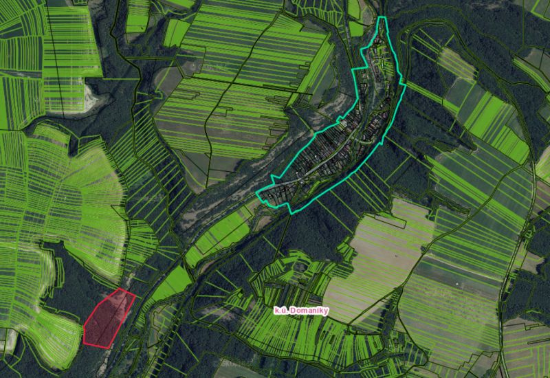 Aerial view of agricultural and forest land around the village of Domaníky.