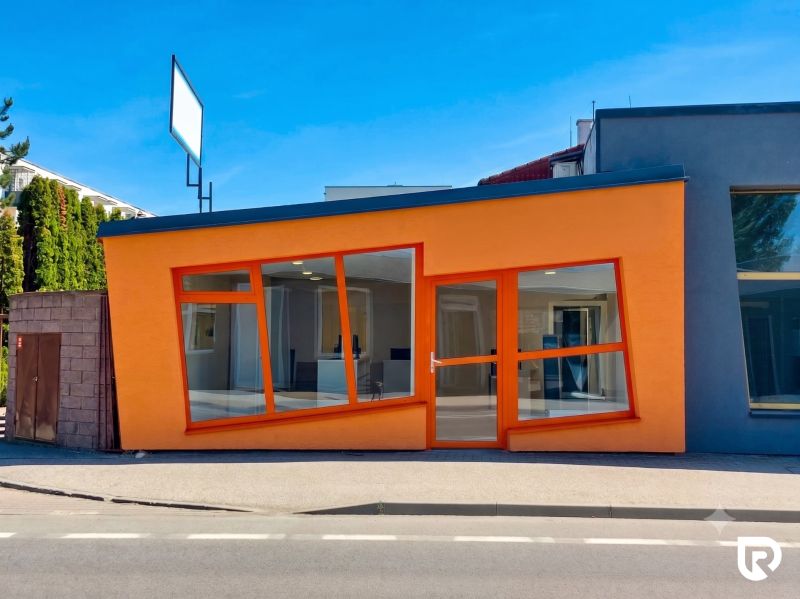 The orange facade of commercial spaces on Zlatovska Street in Trenčín with large glass windows.