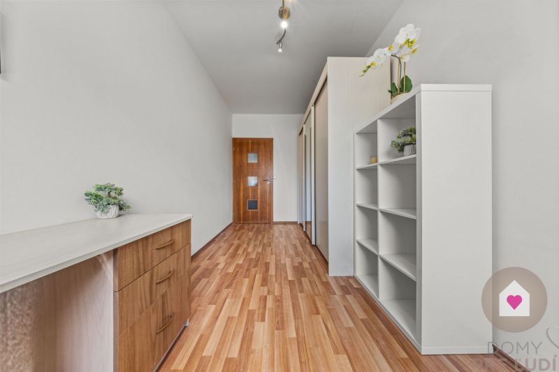 A hallway with a wooden decor floor and white furniture in a 4-room apartment.