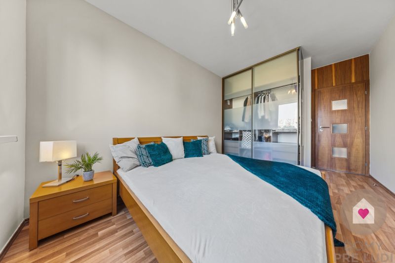 Bedroom in a 4-room apartment with wood-patterned flooring, a wardrobe, and a crib.