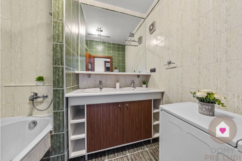 A bathroom with green tiles, a double sink, and a washing machine in a 4-room apartment.