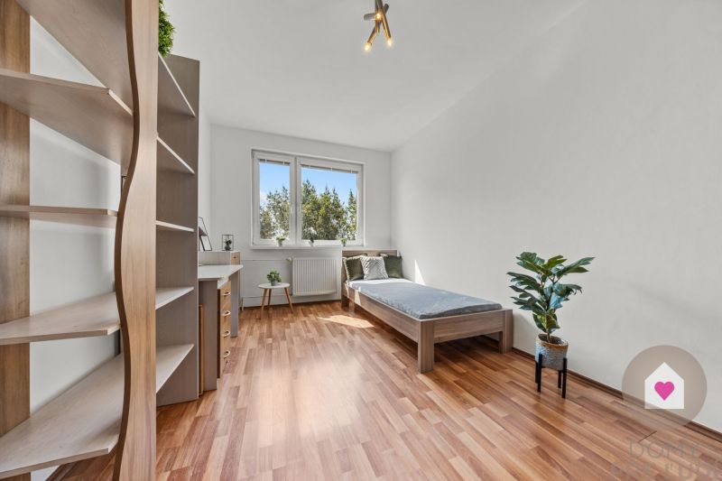 A room in a 4-room apartment with a wooden decor floor, a bed, and a shelf.