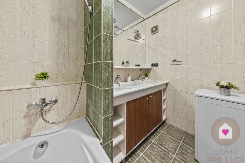 A bathroom with a shower, sink, and washing machine in a 4-room apartment.