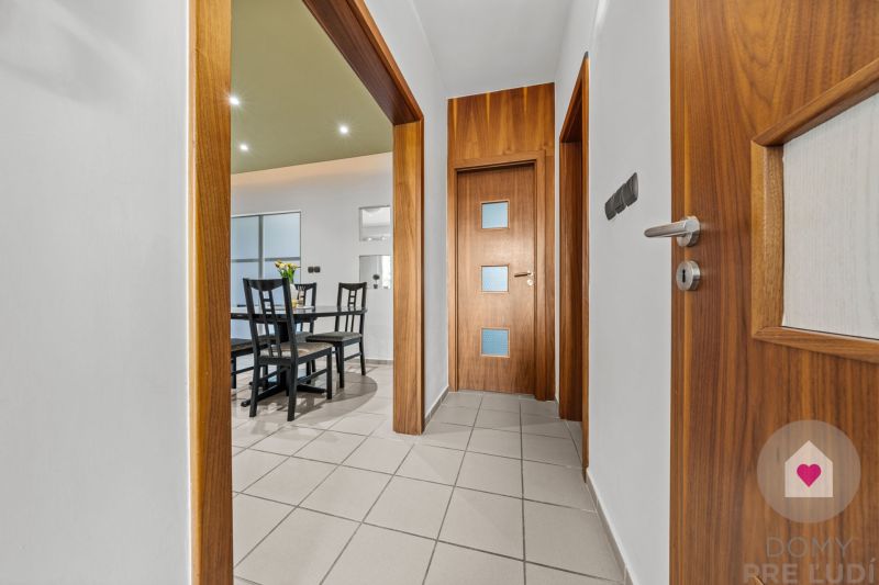 A hallway with a light floor and wooden doors leading to the dining room in a 4-room apartment.
