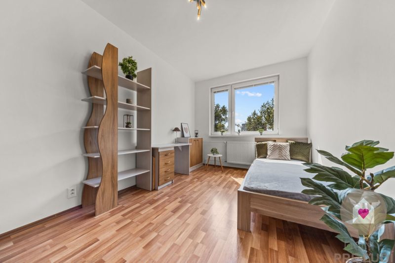 The room in the 4-room apartment has a wooden decor floor, a bed, shelves, and a table.
