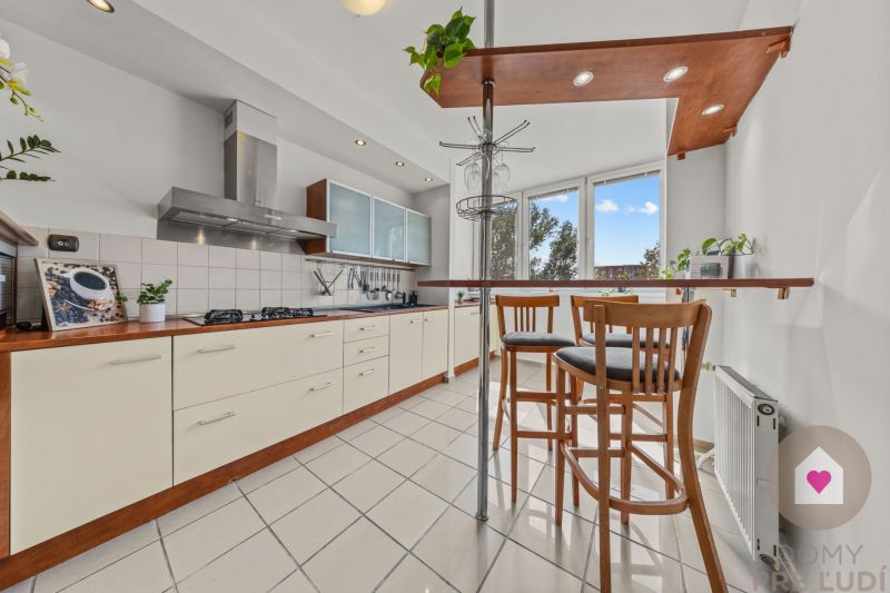 A kitchen in a 4-room apartment with seating at the bar counter and appliances.