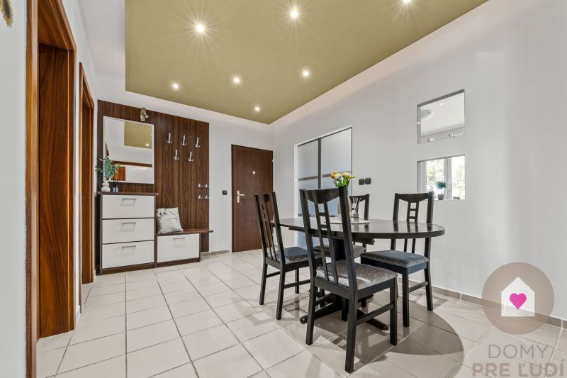 Dining area with a table and chairs in a 4-room apartment, tiled floor.