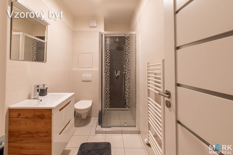 Bathroom in a 2-room apartment with a sink, shower, and toilet, light tiles.