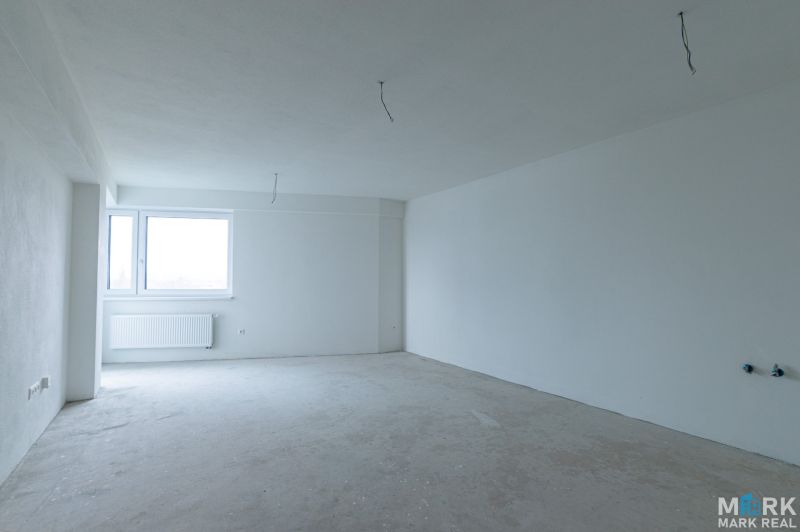 Empty room in a two-room apartment with a window and white walls without furniture.
