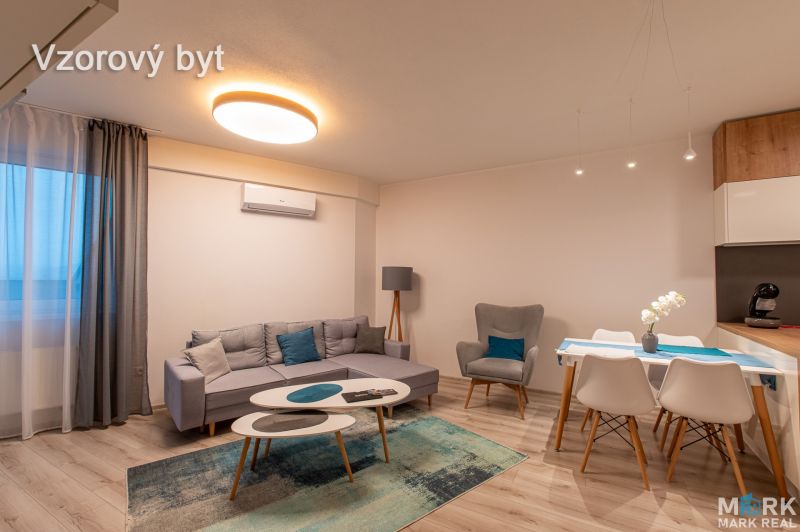 Living room in a 2-room apartment with a sofa, an armchair, and a dining table on a floor with a wooden decor.