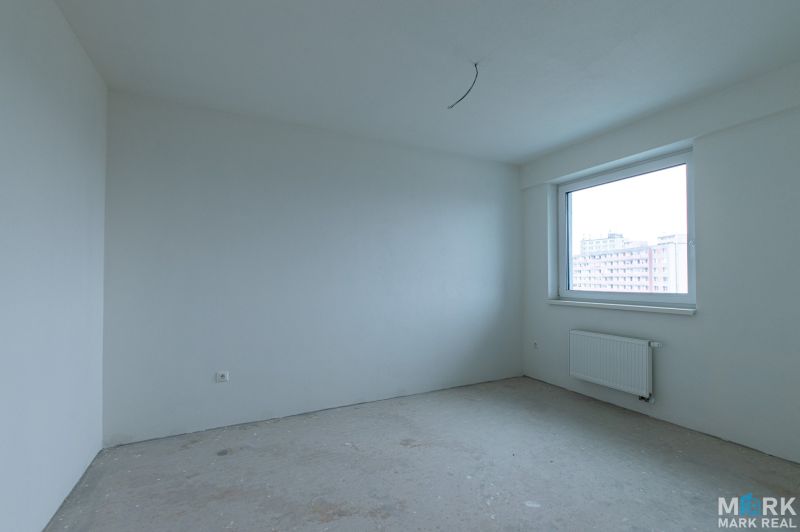 An empty room with white walls in a 2-room apartment, large window, radiator.