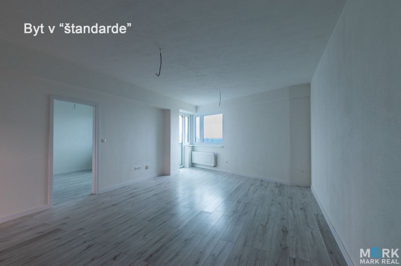 Spacious living room in a 2-room apartment with a wooden decor floor.