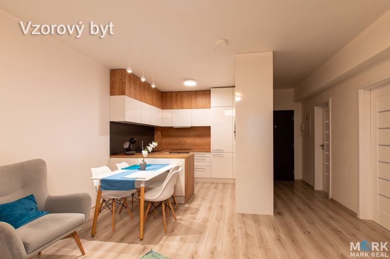 A kitchen with a dining area in a 2-room apartment, a wooden decor floor, and white cabinets.
