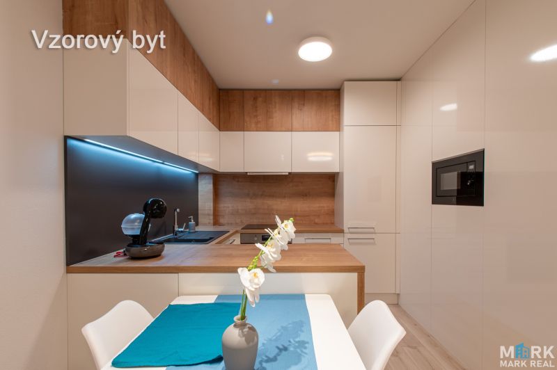 A kitchen in a model 2-room apartment with white cabinets and a wood-patterned floor.