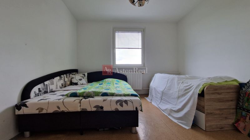 A bedroom with a light floor and two beds in a two-room apartment.