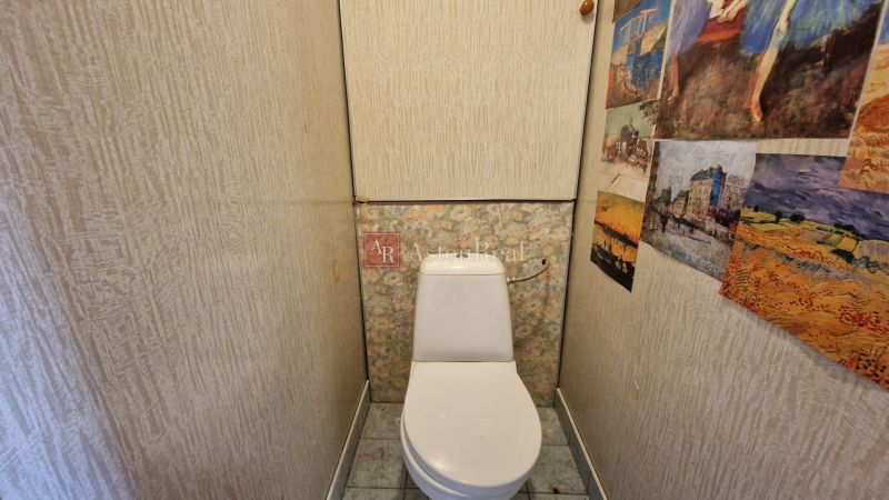 Compact toilet in a 2-room apartment with patterned walls and tiles.