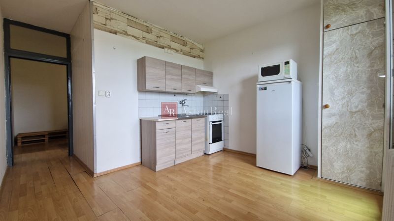A kitchen in a 2-room apartment with a wooden decor floor and basic equipment.