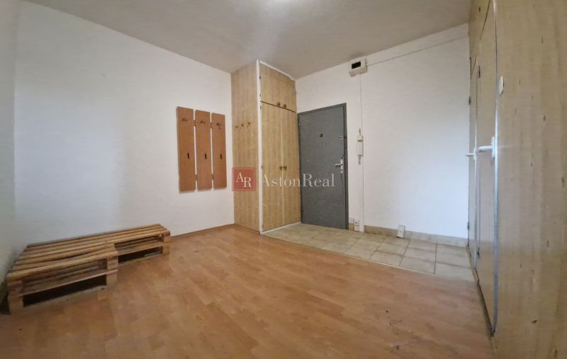Entrance hallway in a 2-room apartment with a wooden decor floor and a coat rack wall.