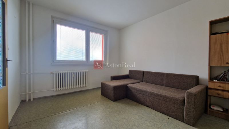 Living room in a two-room apartment with a large window and a comfortable sofa.