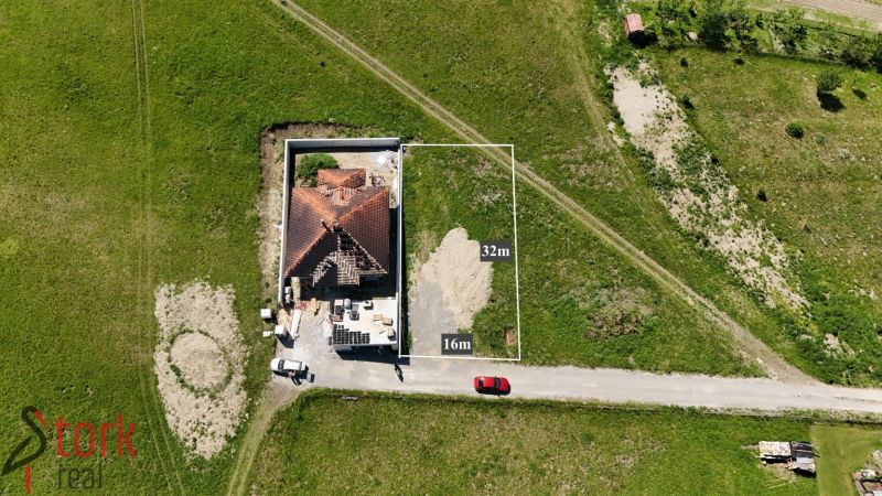 Lietavská Svinná-Babkov: A plot for living, a green meadow with a house under construction and vehicles.