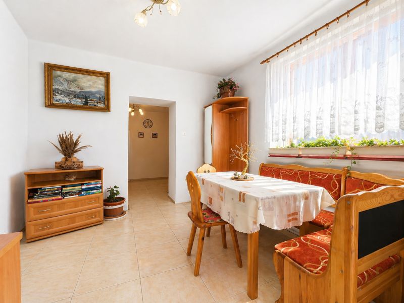 Dining area in a family house with wooden seating, a painting, and floral decorations.